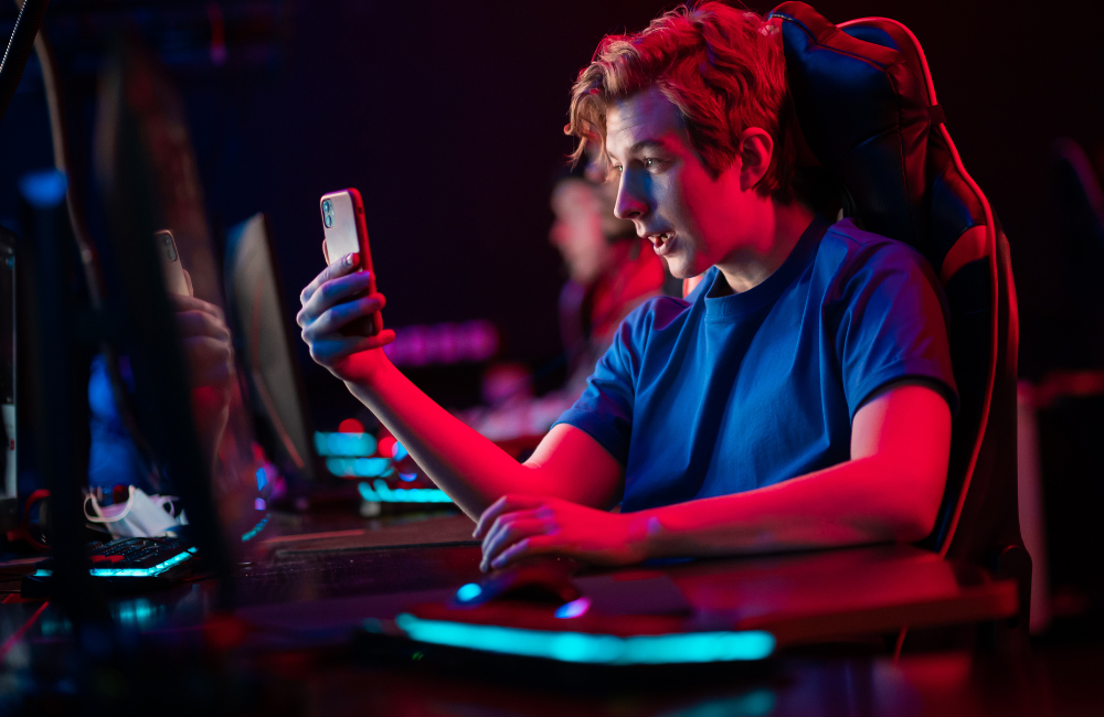 Boy sitting in a gaming chair looking at his phone in amazement